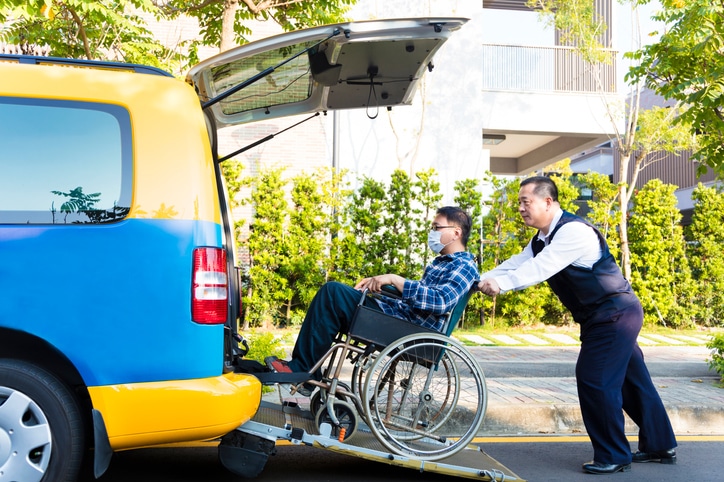 MediStays driver helping NDIS participant on wheelchair getting into taxi
