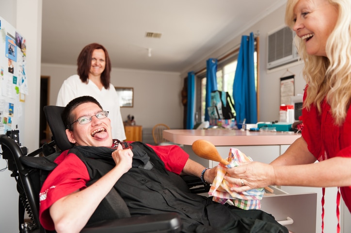 Man in wheelchair with intellectual disability dries dishes with a Support worker for his NDIS Plan goals during MediStays STA