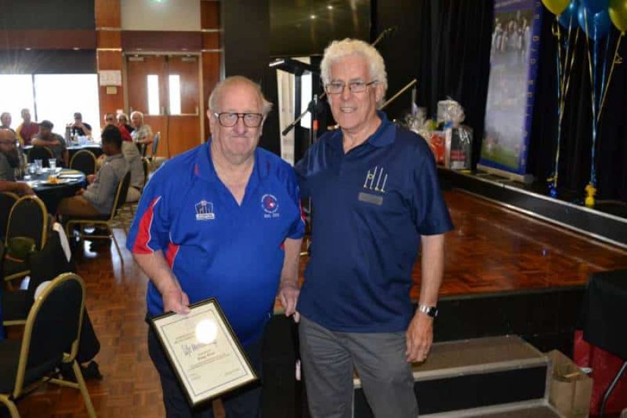 Peter Ryan founder of the Victorian FIDA football leage on right at a club night, with an inclusive footy player on the left receiving an award certificate.